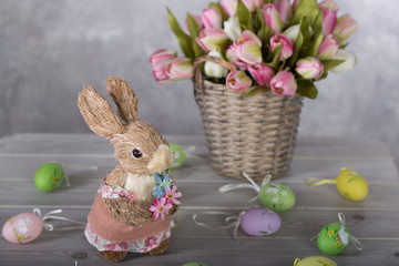 Easter cute bunny sitting with basket of colored eggs on background of spring nature