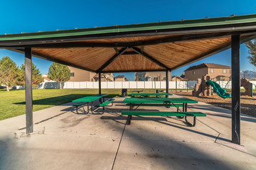 Picnic tables under a wooden roof in a park