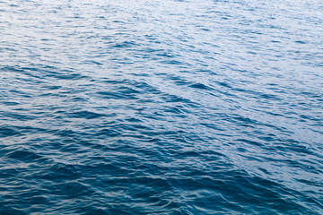 Clear water texture in blue. Background of the ocean and the sea backlit by the sun.