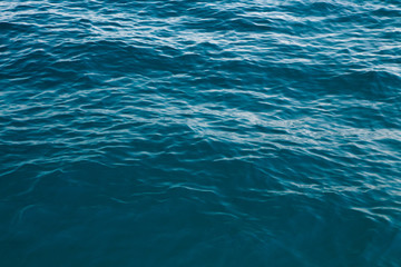 Fototapeta na wymiar Clear water texture in blue. Background of the ocean and the sea backlit by the sun.