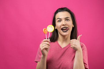 Portrait of lovely sweet beautiful cheerful woman with straight brown hair holding a lollipop near the eyes.