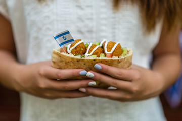 Israeli girl holding pita with falafel and Israeli flag