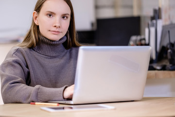 Portrait of lovely young smart female designer working with laptop in an office on manufacture of wooden furniture. ?oncept of women at manufacture work and feminism