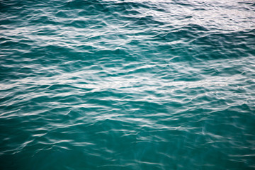 Clear water texture in blue. Background of the ocean and the sea backlit by the sun.