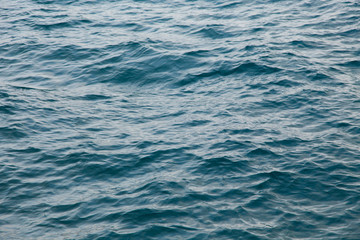 Clear water texture in blue. Background of the ocean and the sea backlit by the sun.