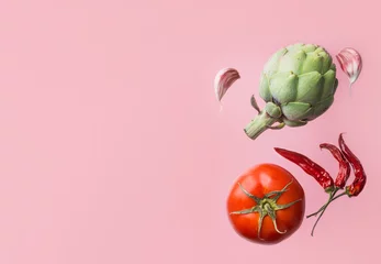 Foto op Canvas Organic vegetables artichoke ripe juicy tomato hot chili peppers garlic cloves floating levitating on pink background. Creative food poster. Mediterranean cuisine healthy diet ingredients © olindana