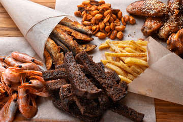 Snack to beer, on a wooden board. Shrimp. Fried fish. Fried peanuts. Fries. Chicken wings.Crunches. Croutons.