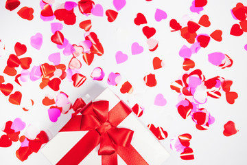 Present box with decorative hearts confetti on white background. Abstract backdrop. Love and romance concept.