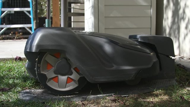 Robotic automower driving into its docking station to recharge batteries during offline lawn mowing hours.