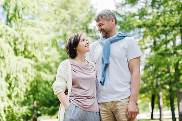 Obraz premium Middle-aged married couple posing at the camera outside.