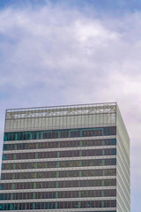 Modern commercial building exterior with tall glass windows against cloudy sky