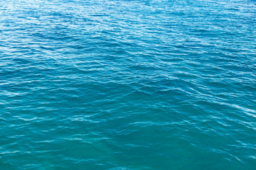 Clear water texture in blue. Background of the ocean and the sea backlit by the sun.