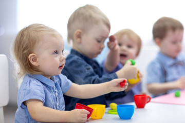 kids group playing with play clay at nursery or kindergarten or primary school