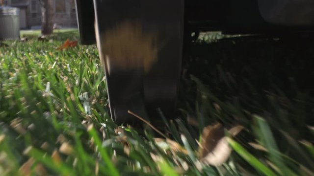 Following robot lawn mower as it trims the grass from behind the wheel at ground level.