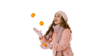 Young attractive woman in a hat and scarf juggles tangerines