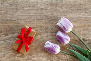 Gift box with tulip flower on the wooden background.
