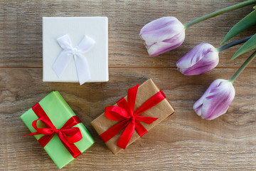Gift boxes with tulip flower on the wooden background.