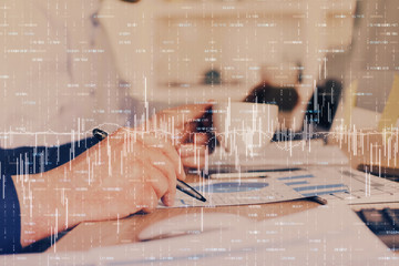 Double exposure of man's hands writing notes of stock market with forex graph.