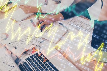 A woman hands writing information about stock market in notepad. Forex chart holograms in front. Concept of research. Double exposure
