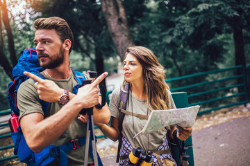 Smiling couple walking with backpacks over natural background