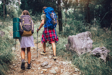 Smiling couple walking with backpacks over natural background