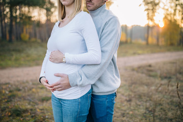 Babybauch in der Herbstsonne Pullover Hände Mutter und Vater Sonnenuntergang