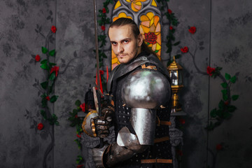 Portrait of a medieval knight with a two-handed sword. Warrior in the studio on a dark background.