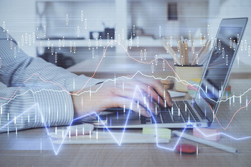 Double exposure of stock market graph with man working on laptop on background. Concept of financial analysis.