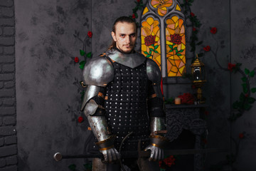 Portrait of a medieval knight with a two-handed sword. Warrior in the studio on a dark background.