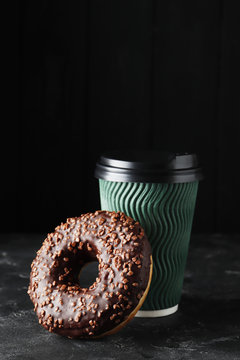 Cup of coffee and sweet tasty donut on a dark background with place for text.