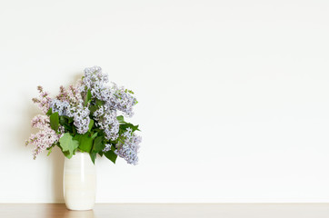 Home decor, lilac flowers in vase on a white wall background. Interior. - Image