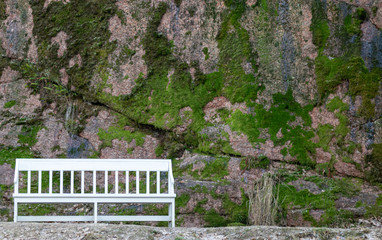 Lonely white bench on the background of rocks