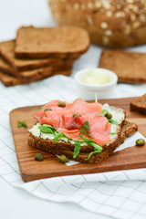 Smoked salmon sandwich with cheese, pistachio and salad leaves, brown breads