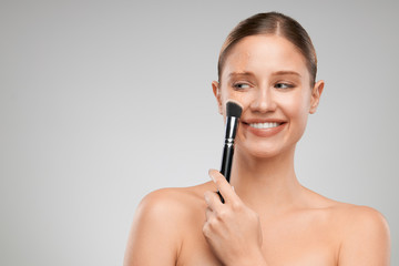 Fototapeta premium Beautiful caucasian girl with pure skin putting on powder.