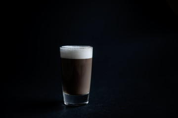 mini cup of cappuccino in a glass cup on black background
