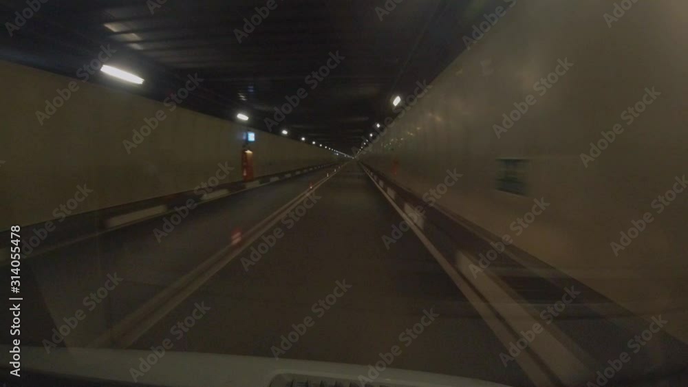 Poster a time laps view of driving in a tunnel, rapidly passing lights of tunnel, traffic guides and instru