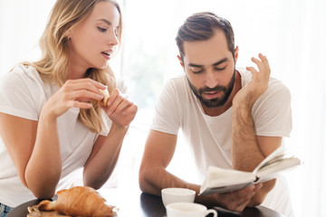 Happy beautiful young couple having breakfast at the kitchen table