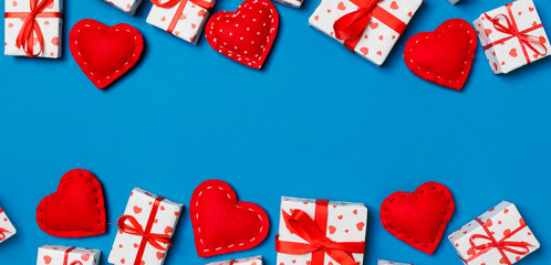 Top view of festive gift boxes and red textile hearts on colorful background with copy space. St Valentine's day concept