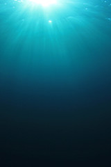 Underwater blue background in ocean with sunbeams