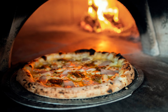 Freshly baked pizza on the background of a burning wood-burning stove