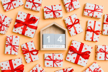 Fototapeta na wymiar Top view of white gift boxes with hearts and wooden calendar on colorful background. The fourteenth of February. Valentine's Day concept