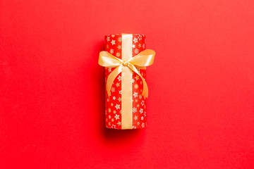 wrapped Christmas or other holiday handmade present in paper with Gold ribbon on red background....