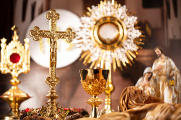 Catholic concept background.  The Cross, monstrance, Jesus figure, Holy Bible and golden chalice on the rustic wooden table.