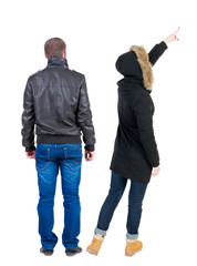 Back view of couple couple in winter jackets pointing.