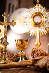 Catholic concept background.  The Cross, monstrance, Jesus figure, Holy Bible and golden chalice on the rustic wooden table.