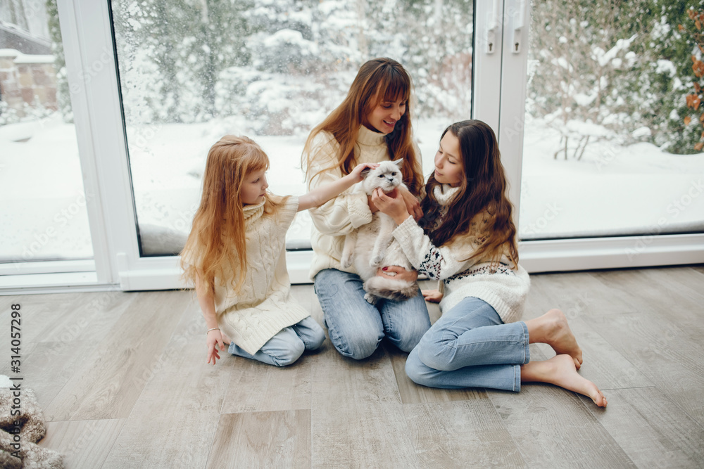 Wall mural Beautiful mother with children. Family at home. People sitting near winter windows