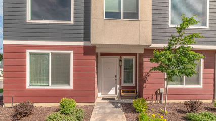 Pano Townhouse facade with red and gray wall and bench by the front door and window
