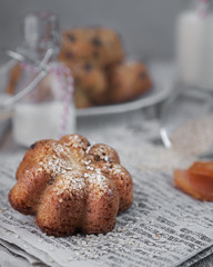 food photography of cake in the shape of a flower with sesame seeds side view with bottles of milk on a gray texture background close up