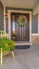 Vertical Porch and facade of home decorated with colorful flowers and wreath on the door
