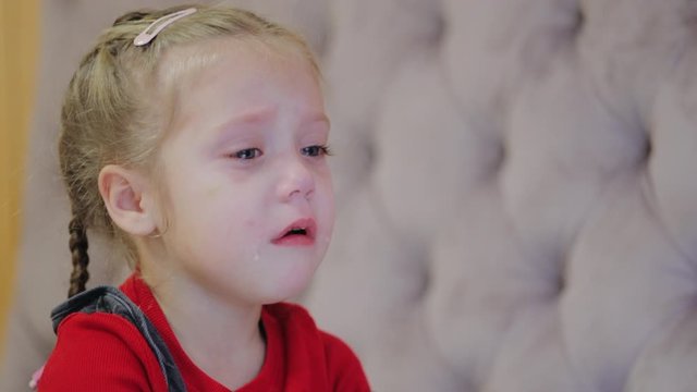 Sobbing pretty preschool girl wipes snot and tears, bad mood, tantrum, child integrity